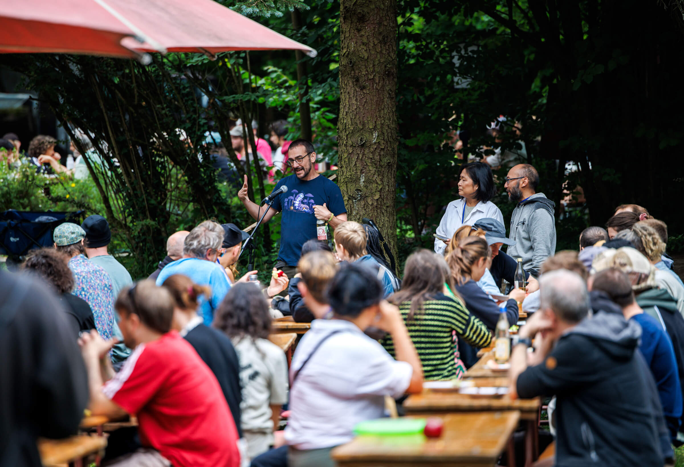 DWeb Berlin Node leader and ZK Video Club founder, Ryan Taylor making announcemnts during a meal. At DWeb Camp, meals are eaten together, with 550 campers served by one common kitchen.